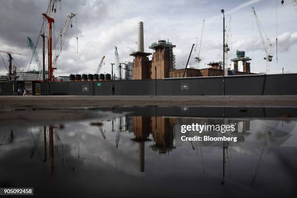 Construction cranes are reflected in a water puddle at the Battersea Power Station office, retail and residential development in London, U.K., on...