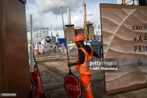Construction worker holds a stop sign as he closes access to the construction site at the Battersea Power Station office, retail and residential...