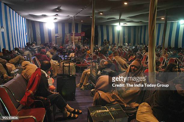 As flights are delayed due to fog, passengers wait inside a tent put up by airport authorities outside the Indira Gandhi International Airport's...