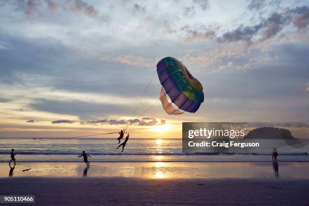 Parasailing off the beach in Phuket. Tourists can take short parasailing flights from the beach out toward the small island, Koh Pu, and back again....