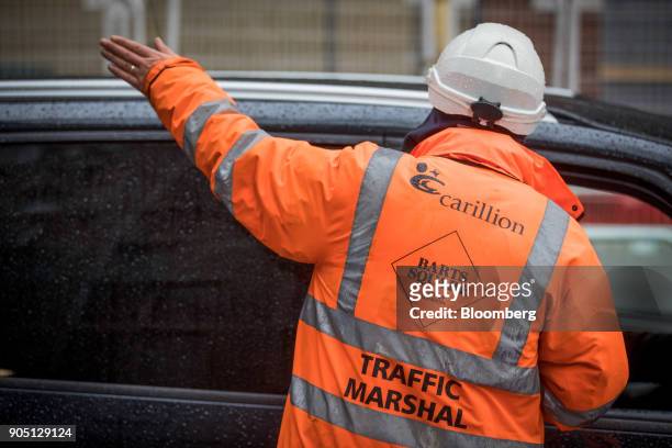 Member of Carillion's staff directs traffic as subcontractors collect their tools on the Barts Square development, operated by Carillion Plc, in...