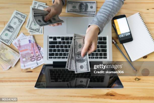 asian business girl holding money and  use smart phone and laptop computer online shopping business - credit report stockfoto's en -beelden