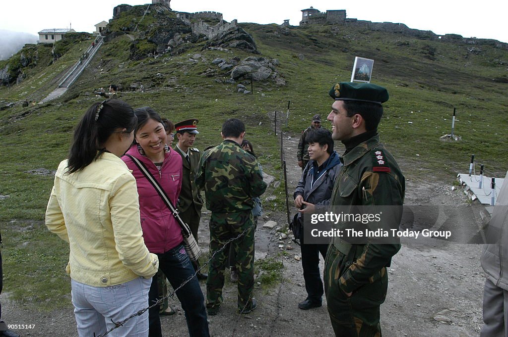 Capt. Neetesh Sharma of the Indian army talks to Chinese civilian girls across the border fence at Nathu La as a Chinese civilian watches on. Trade between India and China is set to begin on July 6th 2006 as the 14000ft high Nathu La pass in Sikkim opens