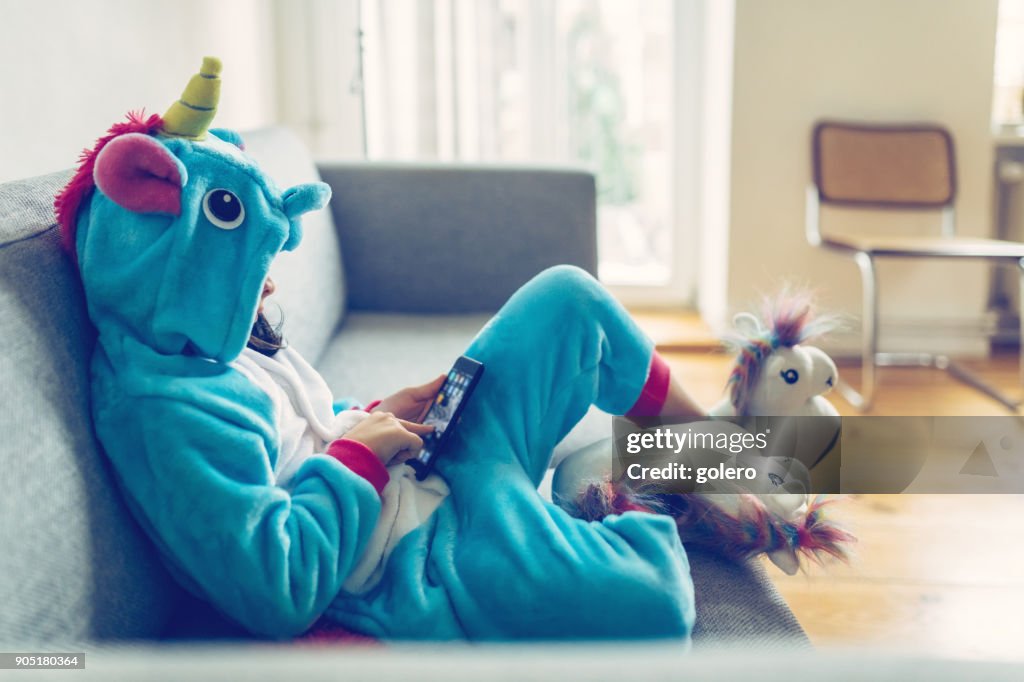 Kleines Mädchen mit Einhorn Kostüm mit Mobile auf couch