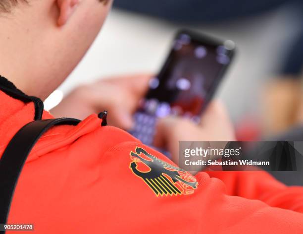 The German eagle is seen on a jacket of an athlete who is using his smart phone at the 2018 PyeongChang Olympic Games German Team kit handover at...