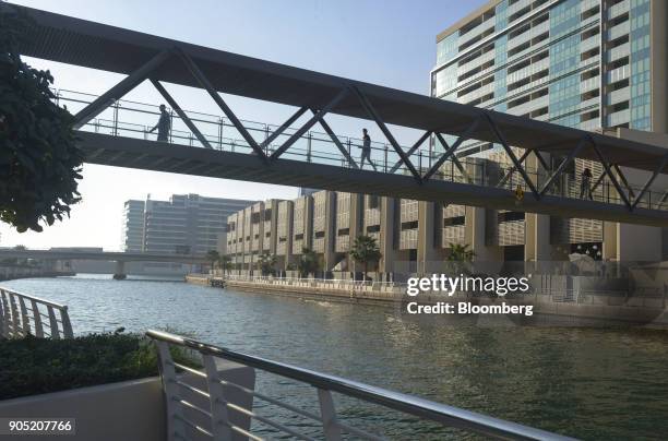 Pedestrians cross a footbridge across a waterway in the Al Muneera gated enclave, developed by Carillion Plc and Al-Futtaim Group, along the Al Raha...