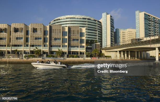 Motor boat passes new residential apartment blocks in the Al Muneera gated enclave, developed by Carillion Plc and Al-Futtaim Group, on the Al Raha...