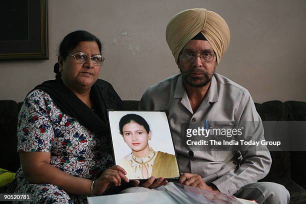 Gurcharan Singh and Manjit Kaur looking at the photo album of their daughter Puneet's marriage , who was killed in 2004 for dowry.