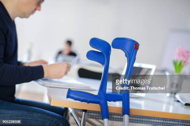 Berlin, Germany Symbolic photo on the topic: Sick at work. A man with crutches sitting at a desk in the office on January 15, 2018 in Berlin, Germany.