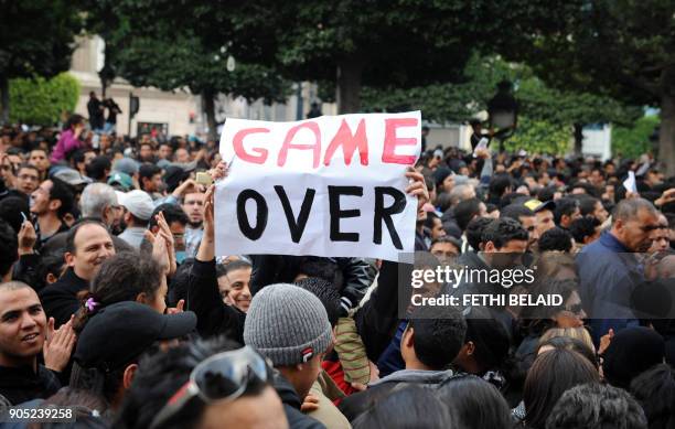 Tunisian demonstrator holds a placard reading "Game Over" during a rally in front of the country's Interior ministry in Tunis on January 14 to demand...