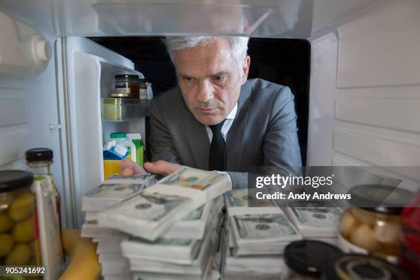 pov man putting stacks of us dollars into a fridge - hiding money stock pictures, royalty-free photos & images