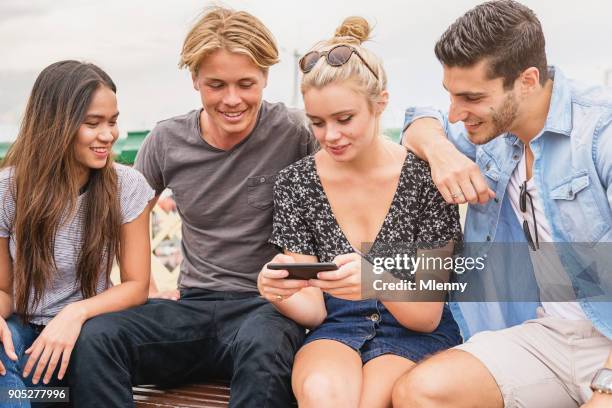 millennial aged friends looking at new smart phone - darling harbour stock pictures, royalty-free photos & images