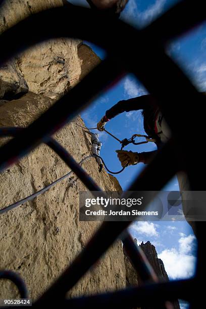 peering up through a climbing rope at a belayer giving slack to a climber. - messa in sicurezza foto e immagini stock