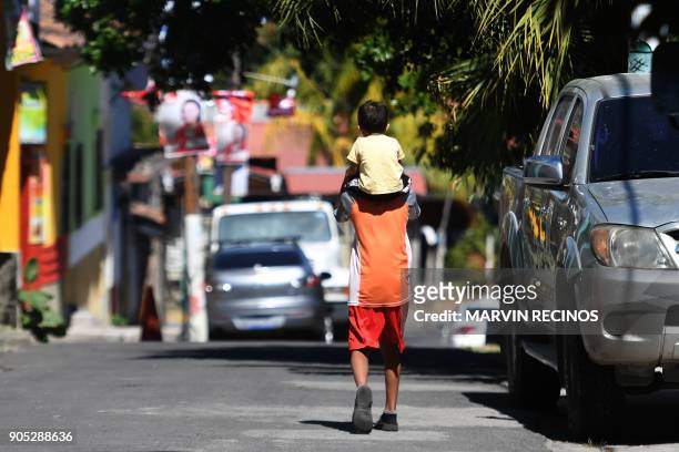 Child is carried on a man's shoulders along a street of San Isidro municipality, Cabanas department, 70 km northeast of San Salvador on January 13,...