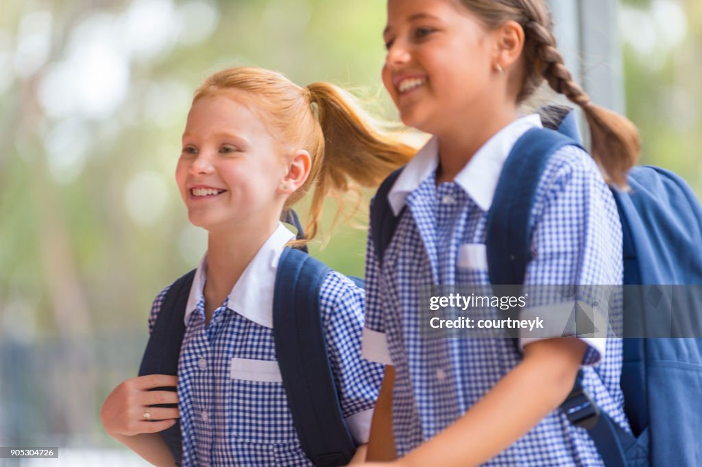 Schoolgirls in uniform with back pack.