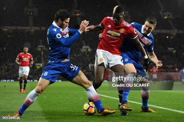 Manchester United's French midfielder Paul Pogba tangles with Stoke City's Egyptian midfielder Ramadan Sobhi and Stoke City's Austrian defender Kevin...