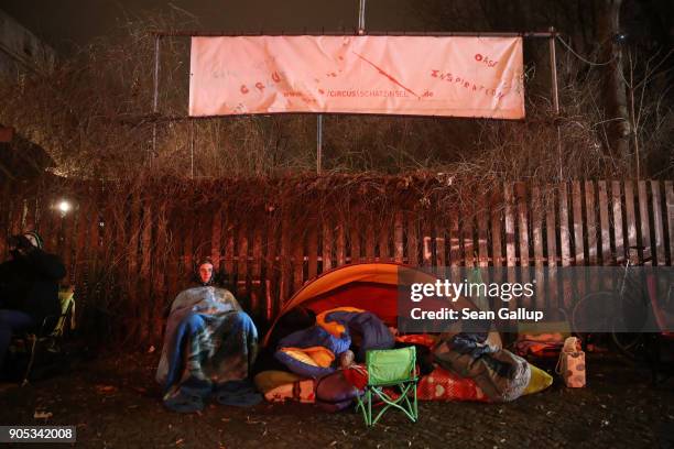 Christopher , who said he has been there since 10pm yesterday and is number 56 on the list, sits with others bundled against the cold across the...