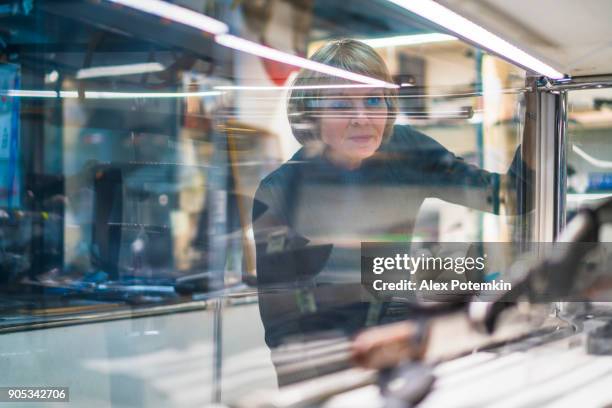mature 50 ans-jolie femme regarde un collection de couteaux à l’écran en verre - 50 year old white woman serious photos et images de collection