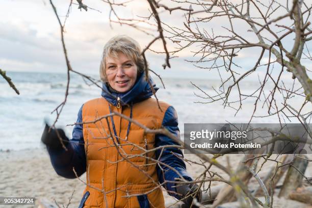 de aantrekkelijke oudere 50 jaar vrouw rusten op het strand van de oostzee - 50 54 years stockfoto's en -beelden