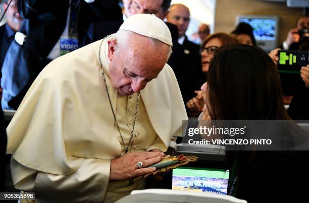 Pope Francis receives an image of Argentina´s Virgen of Lujan as he welcomes journalists on board the plane on the way to Santiago at the start of...