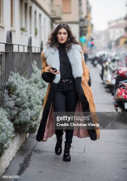 Guest wearing black denim jeans, fur coat is seen outside No21 during Milan Men's Fashion Week Fall/Winter 2018/19 on January 15, 2018 in Milan,...