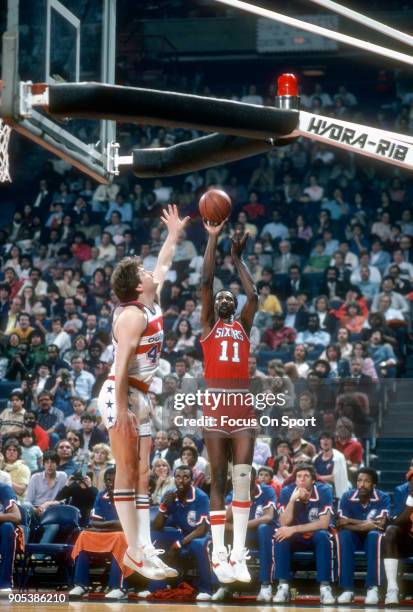 Caldwell Jones of the Philadelphia 76ers shoots over Jeff Ruland of the Washington Bullets during an NBA basketball game circa 1982 at the Capital...