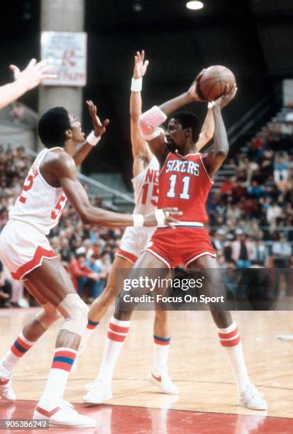 Caldwell Jones of the Philadelphia 76ers looks to pass the ball over the top of George Johnson of the New Jersey Nets during an NBA basketball game...