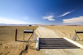 Cattle guard at the intersection between the C37 and D31 roads between the towns Noordoewer, Ai-Ais Fish River Canyon and Aussenkehr. Gravel roads, mountains and desert sand in the background.