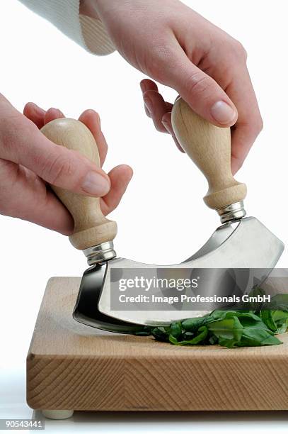 human hand chopping basil with mezzaluna on chopping board - mincing knife stock pictures, royalty-free photos & images