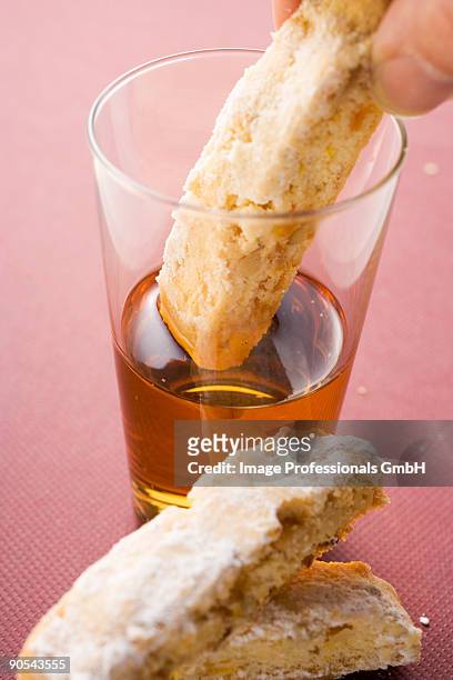 hand dipping cantucci (italian almond biscuit) into glass of vin santo - wine glass finger food stock-fotos und bilder