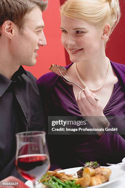 woman feeding man in restaurant, smiling - steak holder stock pictures, royalty-free photos & images