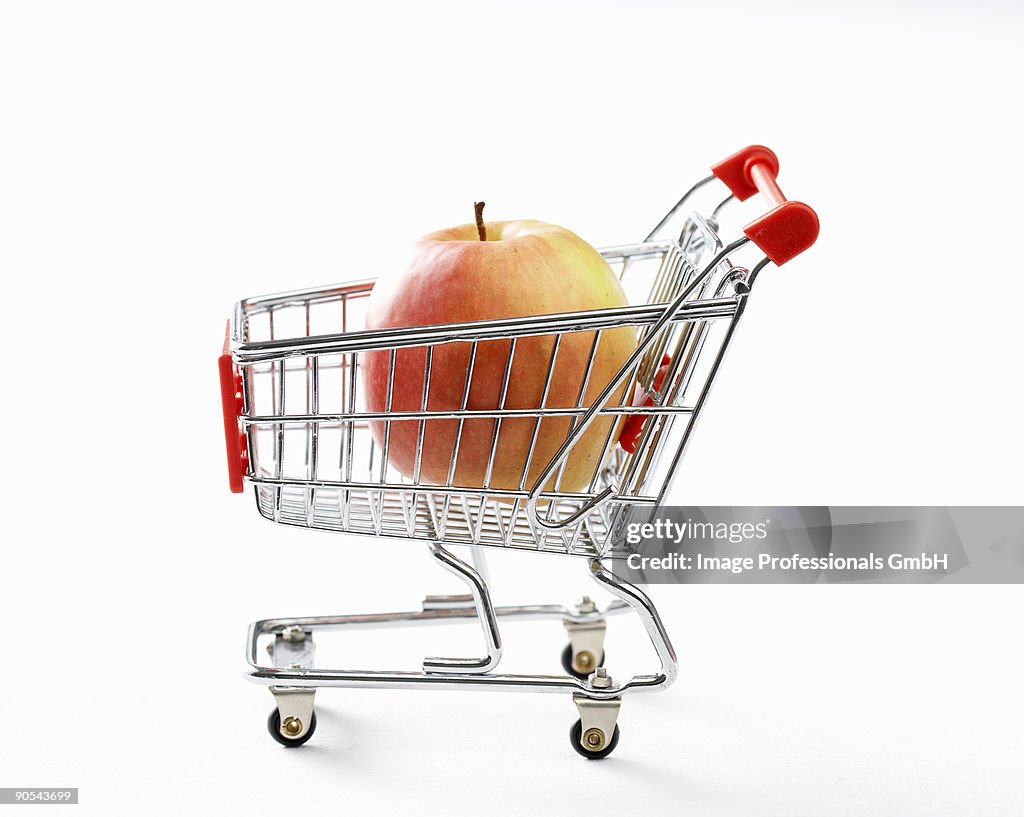 Apple in toy shopping trolley, close up