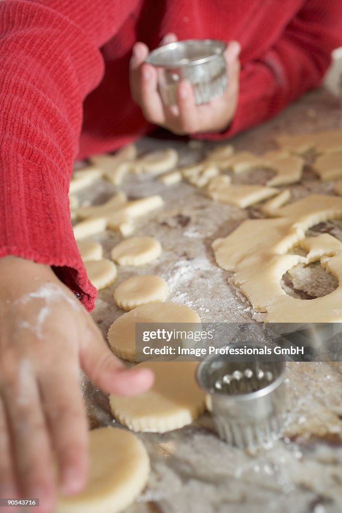 Girl (4-5) cutting out biscuits, close up, mid section