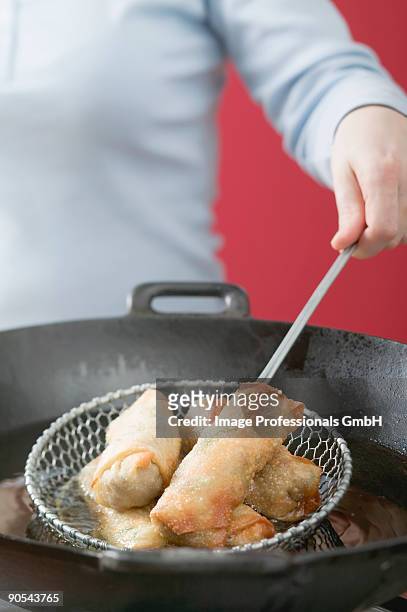 deep-frying spring rolls in wok, close up - schuimspatel stockfoto's en -beelden