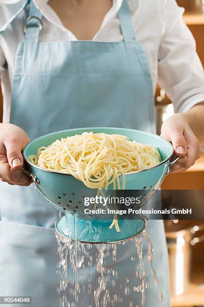 woman draining cooked spaghetti, close up, mid section - scolapasta foto e immagini stock