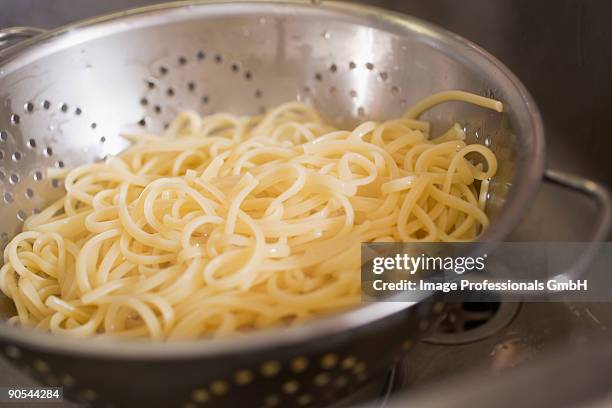 draining cooked ribbon pasta in colander, close up - scolapasta foto e immagini stock