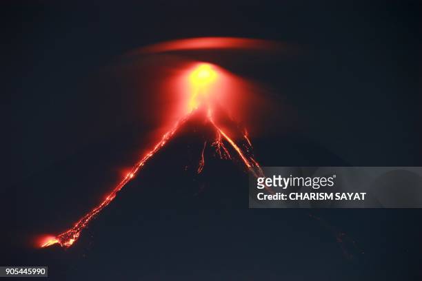 This photo taken on January 15, 2018 shows lava cascading the slopes of Mayon volcano as it erupts, as seen from Legazpi City in Albay province south...