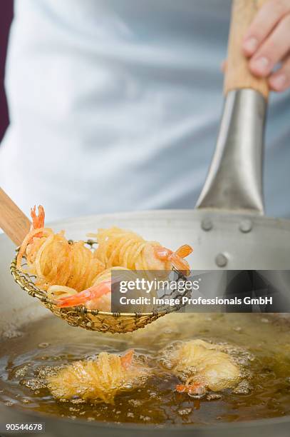 deep-frying noodle-wrapped prawns in wok, close up - schuimspatel stockfoto's en -beelden