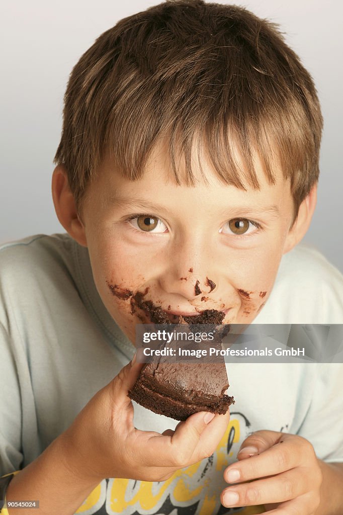 Boy (6-9) eating chocolate cake, close up, portrait