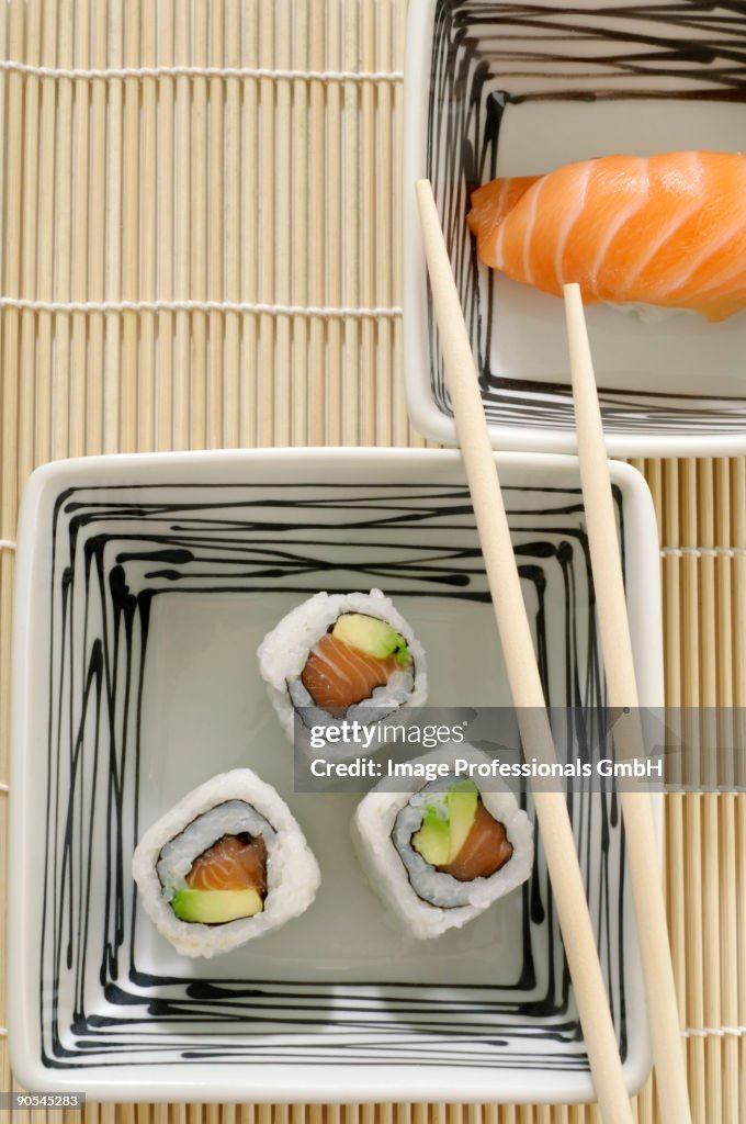 Three maki sushi and one nigiri sushi in square dishes, overhead view
