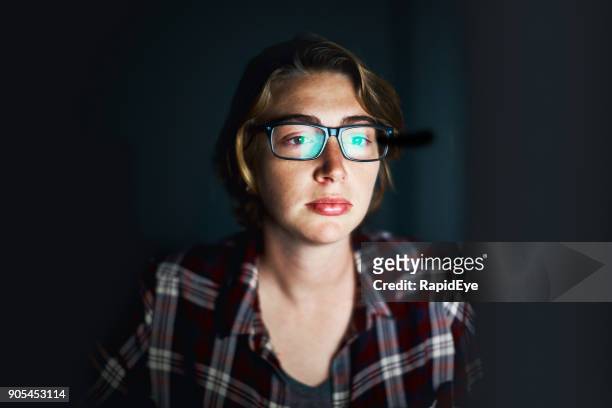 young woman in the dark stares at computer monitor - romance fraud stock pictures, royalty-free photos & images