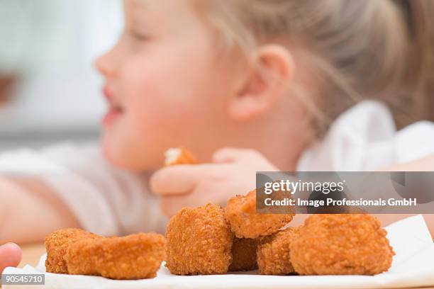 girl (4-5) eating chicken nuggets, close up - eating nuggets stockfoto's en -beelden