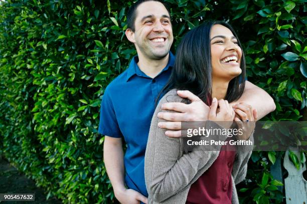 portrait of smiling couple hugging near leaves - ritratto coppia mista foto e immagini stock