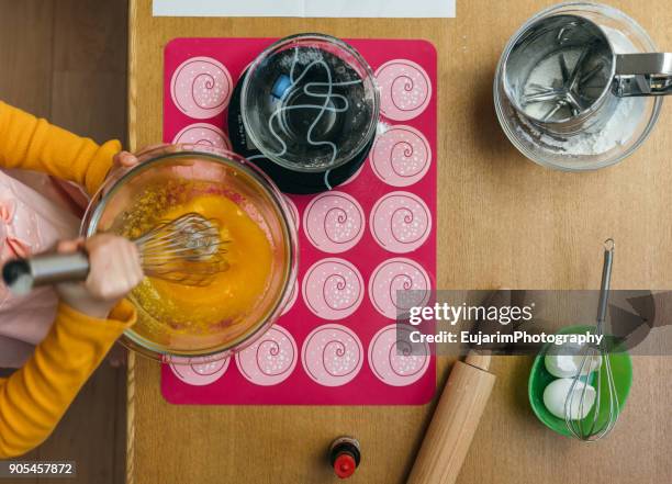 child beating eggs, flour, sugar and butter in a mixing bowl - flour sifter stock pictures, royalty-free photos & images