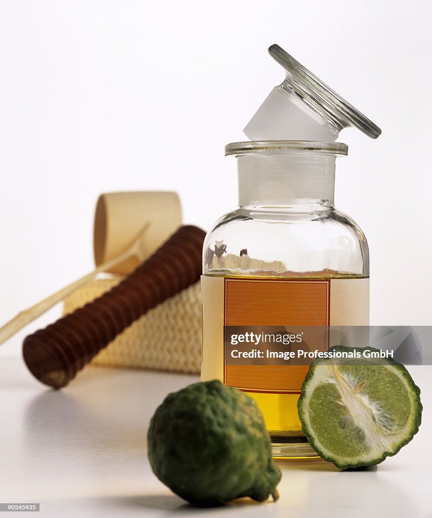 Bergamot oil in bottle, massage equipment and kaffir lime, close up