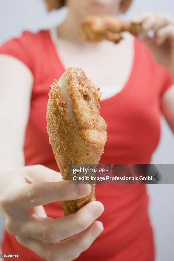 Woman eating fried chicken drumsticks