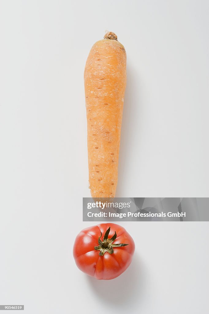 One carrot and one tomato forming an exclamation mark