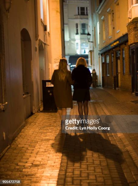 two woman walking in alleyway at night - lyn holly coorg stock pictures, royalty-free photos & images