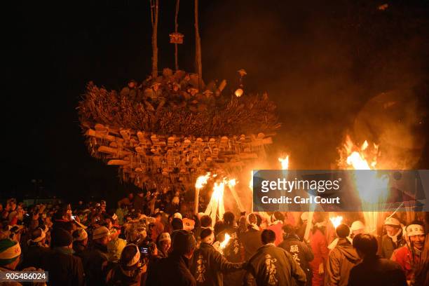People carry flaming sticks as they try to set fire to a wooden shrine that is protected by men from Nozawaonsen village during the Nozawaonsen...