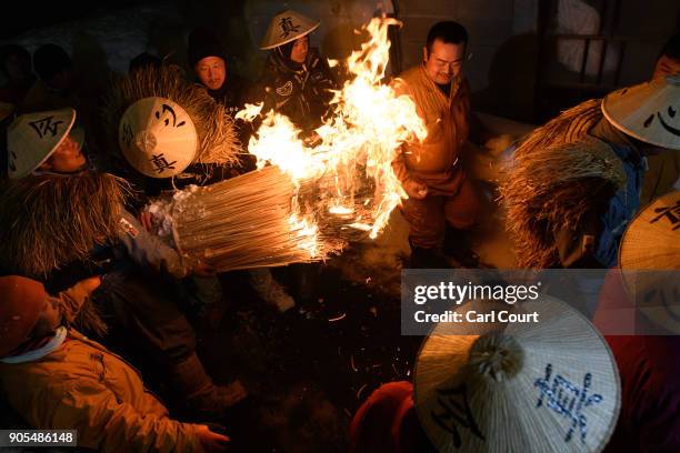 Men carry a flaming bundle of sticks towards the shrine as they begin the Nozawaonsen Dosojin Fire Festival on January 15, 2018 in Nozawaonsen,...